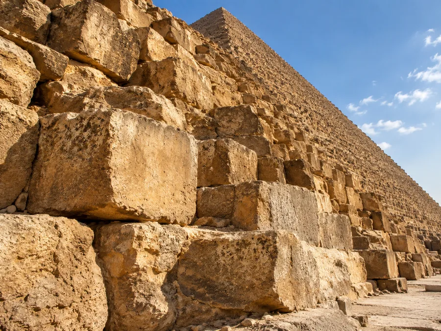 Die riesigen verwitterten Kalksteinblöcke am Fuß der Cheops-Pyramide in warmem Seitenlicht